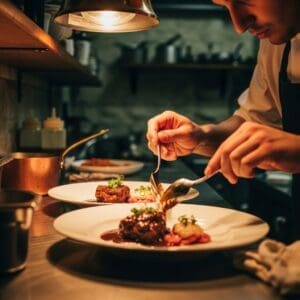 Chef plating a classic Piedmont dish such as brasato al Barolo or vitello tonnato at a rustic kitchen pass, warm tones and shallow depth of field.