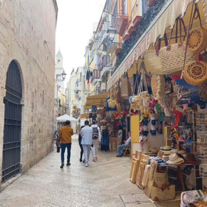 Travelers exploring the historic streets of Bari with traditional stone buildings.