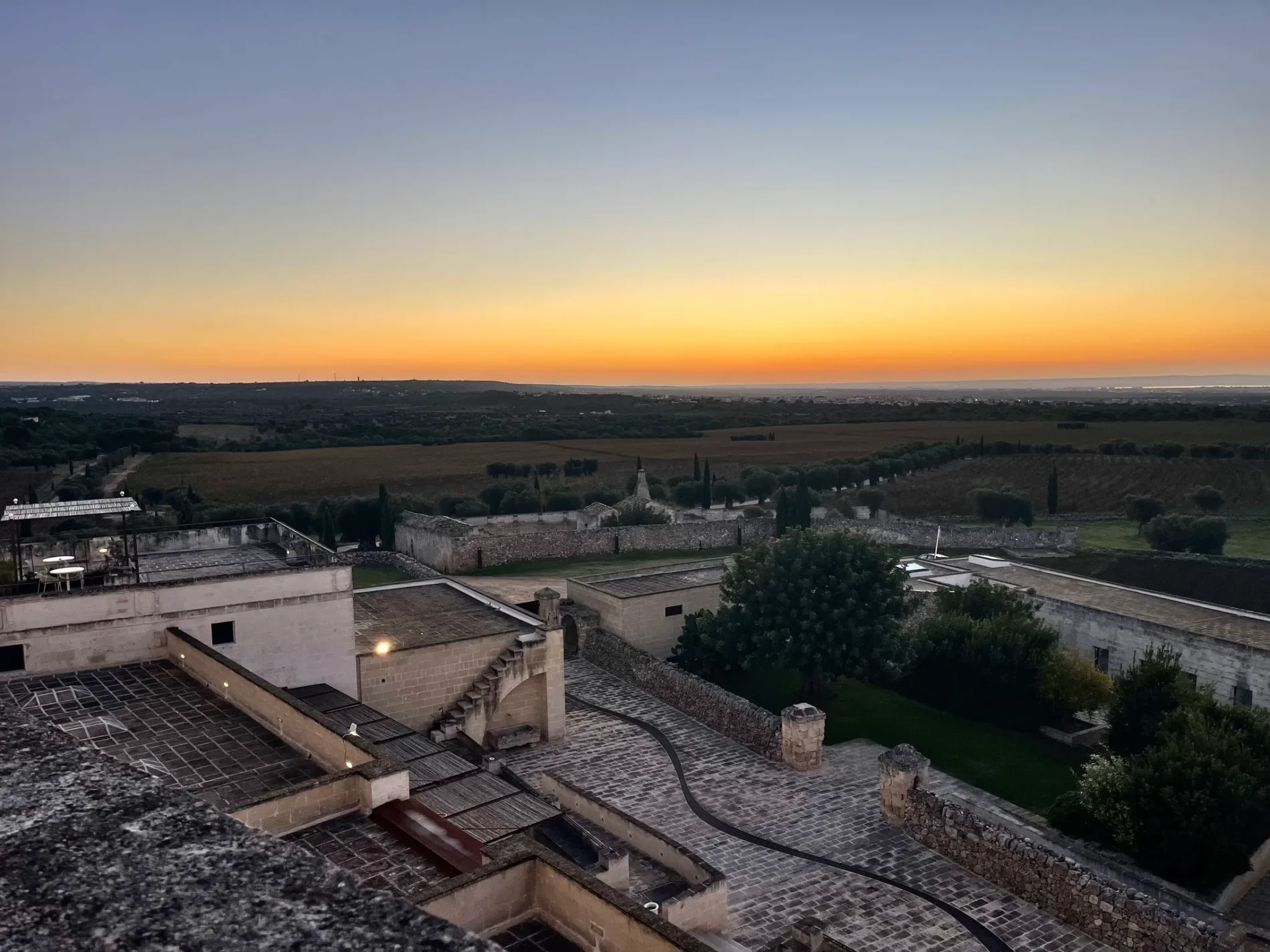 Sunset view over Amastoula Wine Resort, showing stone structures and agricultural land.