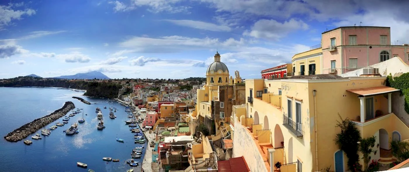 Panoramic view of Marina Corricella, a colorful coastal village in Campania, Italy, with a harbor full of boats.