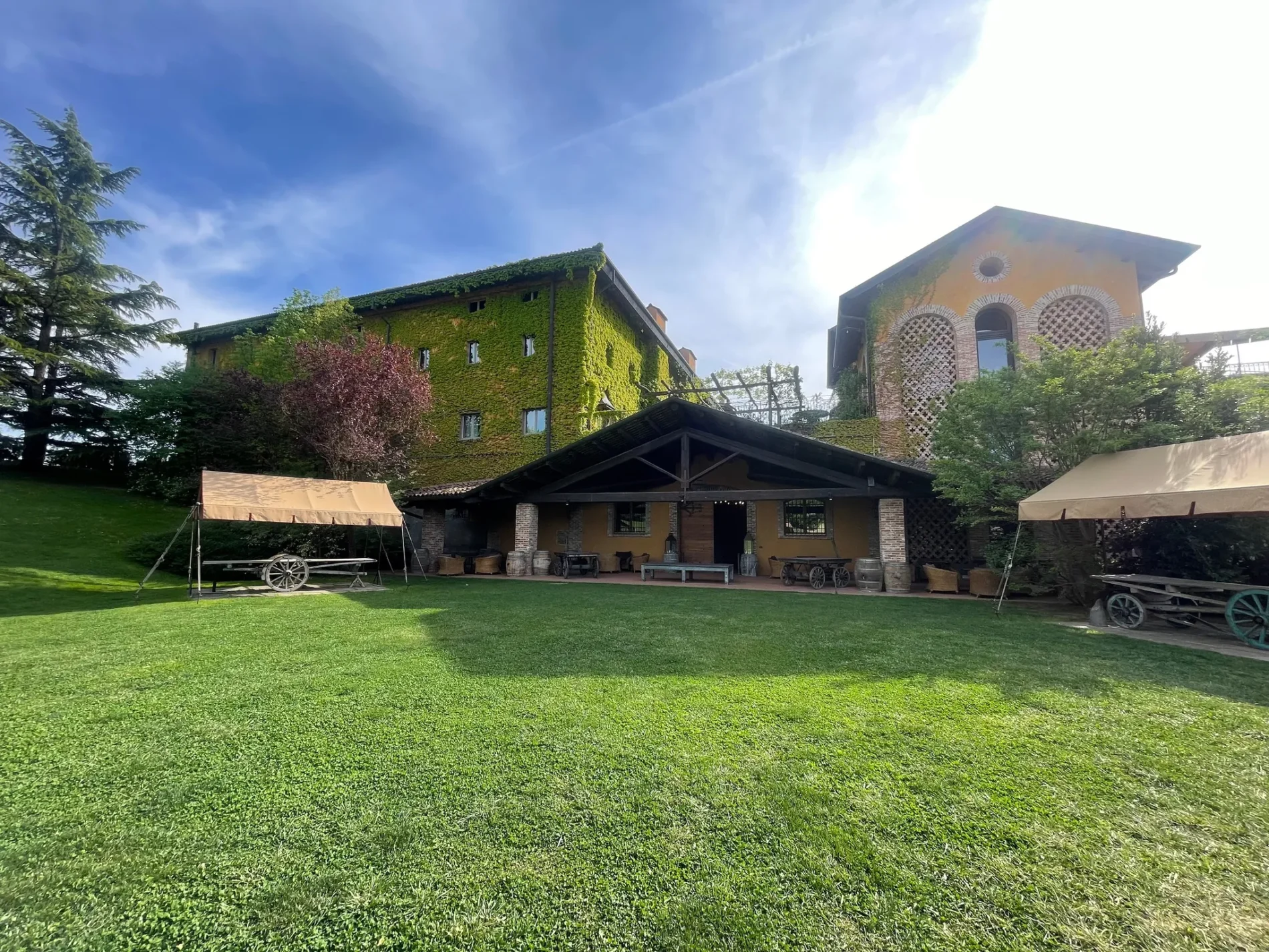 Villa Sparina Resort with ivy-covered buildings, green lawn, and outdoor seating under a bright blue sky.