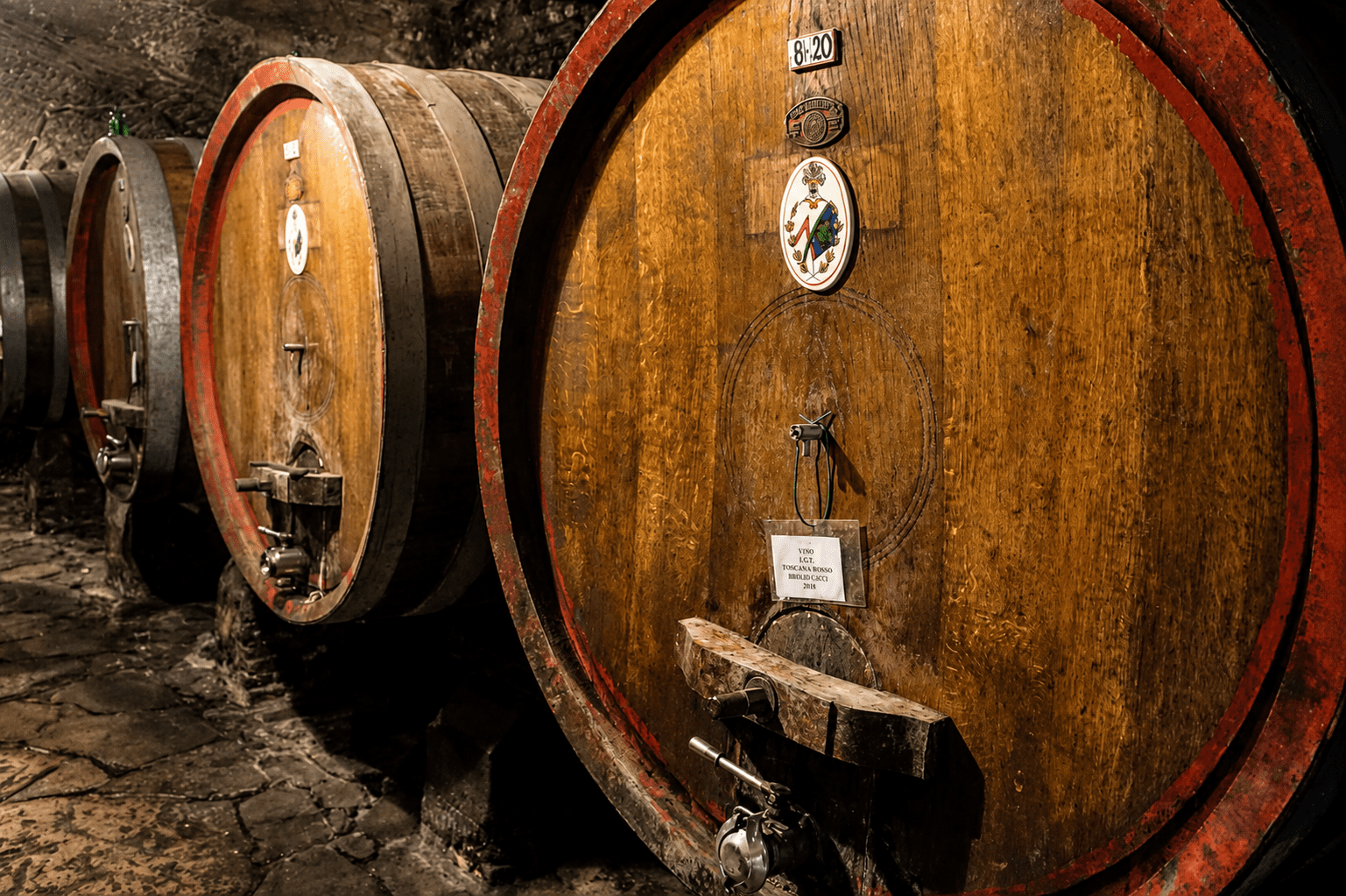 Aged wine barrels in a private Tuscan cellar, the access insiders get when visiting vineyards in Tuscany.