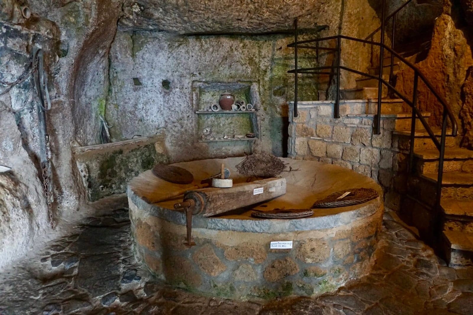 Ancient olive oil mill with a stone crushing basin inside a cave at Antico Frantoio in Italy